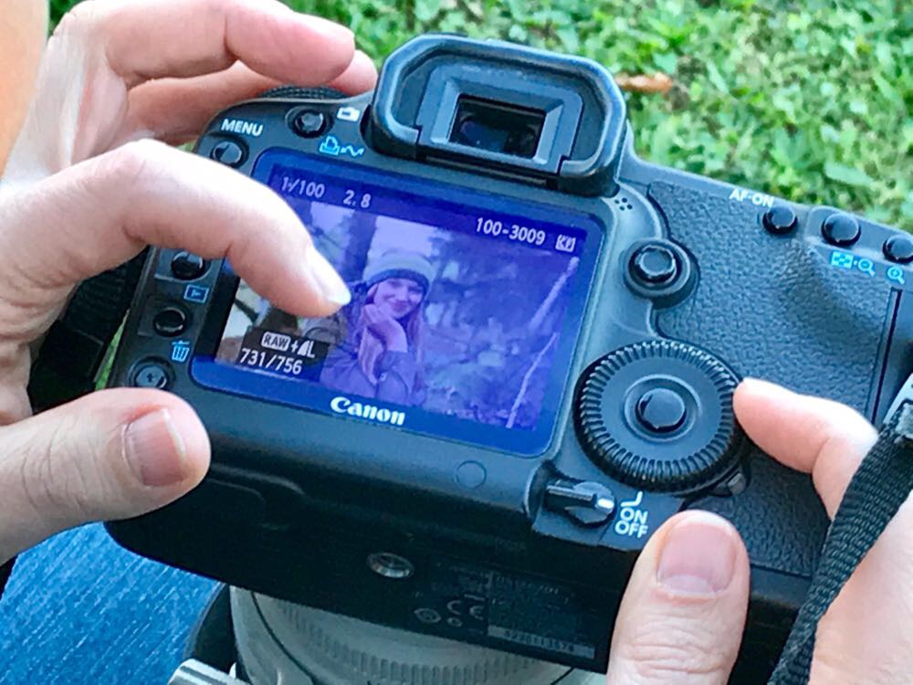 Fotografin überprüft die geschossenen Fotos in der Vorschau auf dem Display ihrer DSLR-Kamera direkt nach dem Shooting.